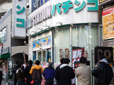 Oblique view of BB Station Nippori with its curved sign and street-level entrance